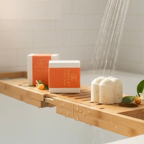 Bath caddy with soap, towels, and a shower head in a bathroom setting