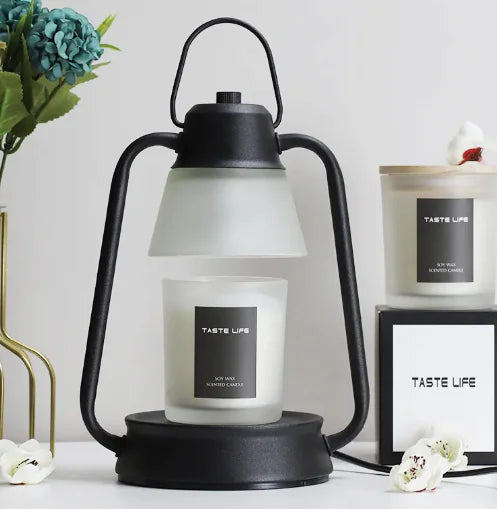Black lantern with a white candle labeled 'Taste Life' on a white surface with decorative elements.