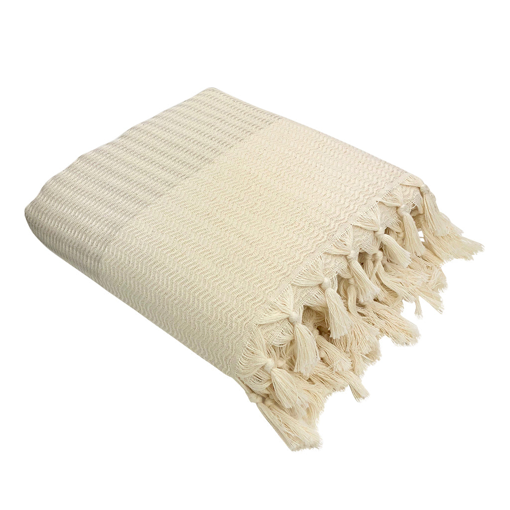 Beige woven blanket with tassels on a white background