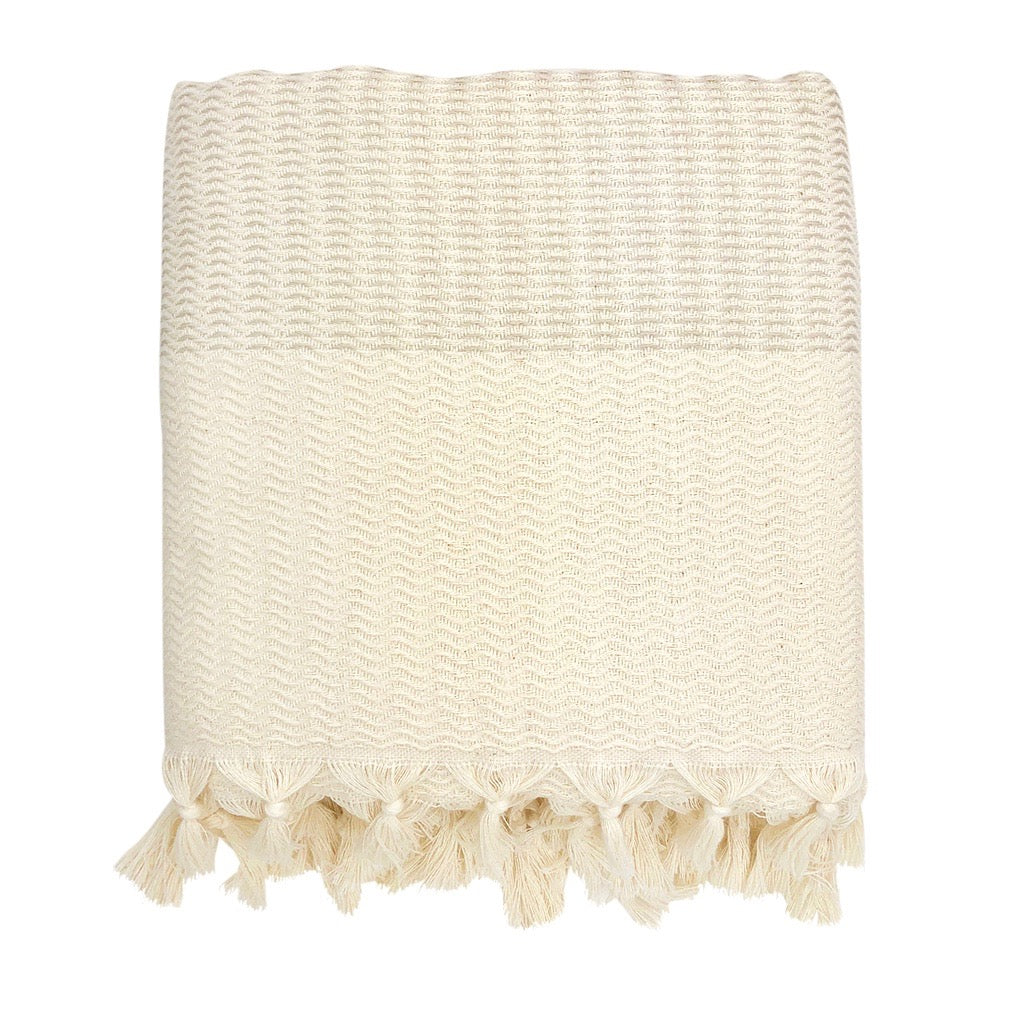 Beige woven blanket with tassels on a white background