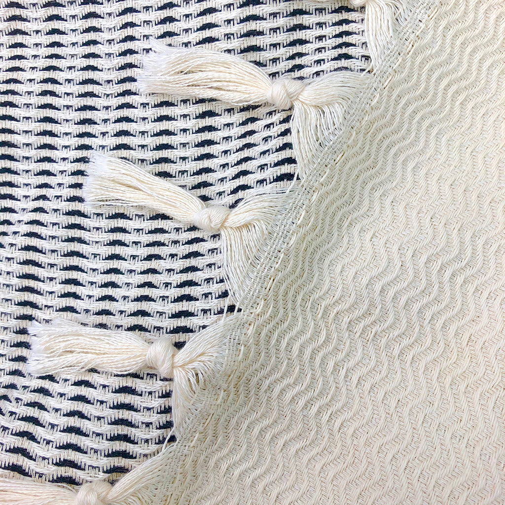 Textile with wavy pattern and tassels on a striped background